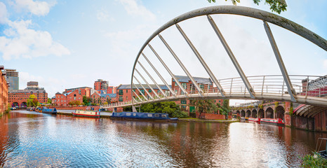Waterway canal area with a narrowboat on the foreground modern bridge, Castlefield district