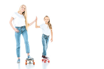 Fototapeta premium happy mother and kid giving high five while riding penny boards on white