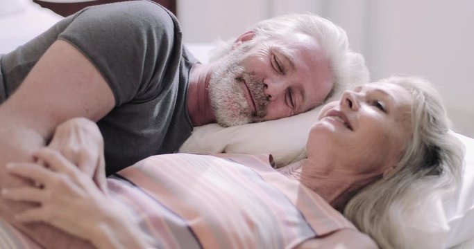 Senior Adult couple on holiday talking in hotel bed