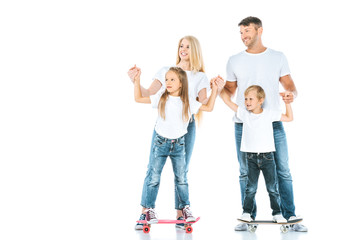 Obraz premium happy parents near holding hands of children riding penny boards on white