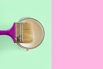 Purple brush with open can of white paint on neo mint and pink background. Trend repairs concept.