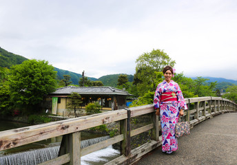 Fototapeta na wymiar KYOTO, JAPAN - MAY 9, 2017: Asian woman dressing kimono and standing by wooden balcony in cloudy day, Kyoto Japan