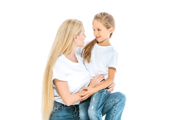 happy mother and cute daughter looking at each other isolated on white