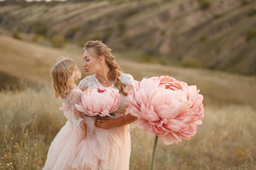 Mom with daughter in pink fairy-tale dresses walk in nature. The childhood of the little princess....
