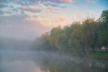 Fall colour reflected in the still waters of foggy morning Lake in Hungary