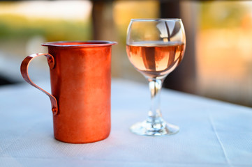 a glass of rose wine on the table in the restaurant and a copper bowl