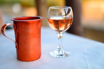 a glass of rose wine on the table in the restaurant and a copper bowl