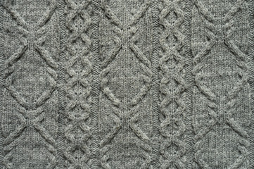 Seamless gray knitwear fabric texture with pigtails. Knitting texture of sweater or scarf or plaid. Knitted grey background. Close up, top view.