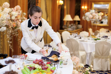 Waiters set the tables in the restaurant for the banquet