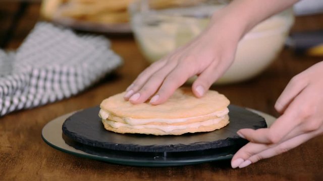 Making layers of Napoleon cake at home: putting custard on baked pastry.