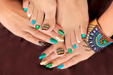 Multicolored pedicure and manicure with rhinestones on oval long female nails.Nail design with...
