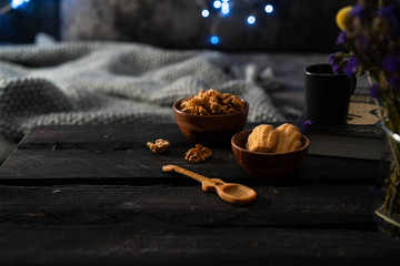 Madeline cookies, in a wooden bowl, walnuts in a bowl, dark Woden backdrop, festive lights background, cozy living room interior