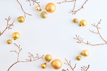 Flat lay frame with gold christmas balls and branches on a white background