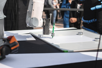 Robotic hand draws a picture with a green pen. Science and high technologies concept.