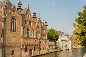 Fototapeta premium Bruges, Belgium. Medieval ancient houses made of old bricks at water channel with boats in old town. Picturesque landscape.