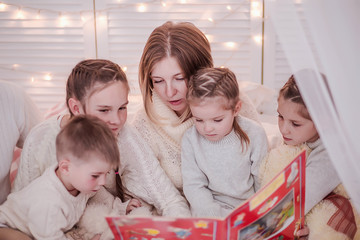 Mother with many children reads Christmas tales to children