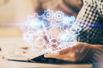 Fototapeta premium Double exposure of Man writing in notepad with business icons on background.