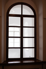 Fototapeta premium Large window with rounded top. Dark brown trims. Warm tone. Vertical orientation.
