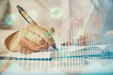 Multi exposure of woman's hands making notes with forex graph hologram. Concept stock market...