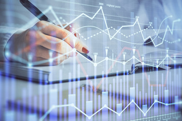 Multi exposure of woman's hands making notes with forex graph hologram. Concept stock market...
