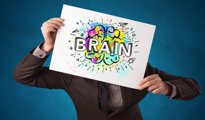 Young person holding white paper in front of her head with colorful brain concept