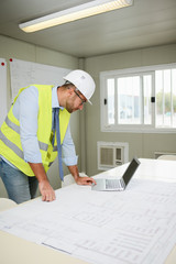 portrait of handsome foreman construction worker man on an industrial building industry construction site studying blueprint indoor