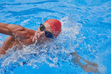 Fototapeta premium Swimmer in an outdoor pool, swimming in a crawl style, taking his head out of the water to breathe, side view and from above