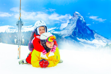 Mother and daughter skiers lying on a snowy slope, ski resort
