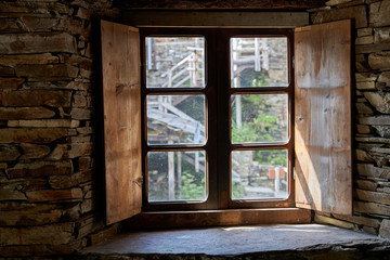 vista del exterior a través de una ventana de madera y paredes de piedra 