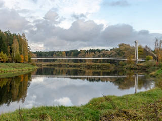 autumn landscape with river, bridge and beautiful colorful trees, river Gauja, Valmiera, Latvia