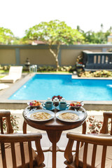 Balinese tropical breakfast of fruit, coffee and omelet for two people. on the street near the pool