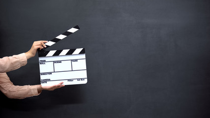 Female hands using clapperboard against black background, shooting movies - 295353602
