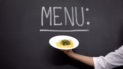 Hand showing plate with pasta on Menu background, delicious cooking recipes