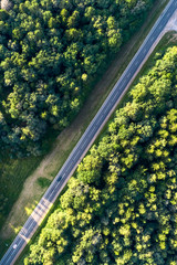 Asphalt highway passing through the forest. Aerial view, vertically from top to bottom - obrazy, fototapety, plakaty