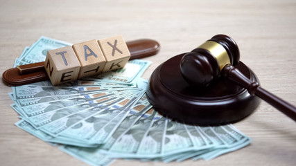 Dollars and tax word made of wooden cubes table, gavel lying on sound block