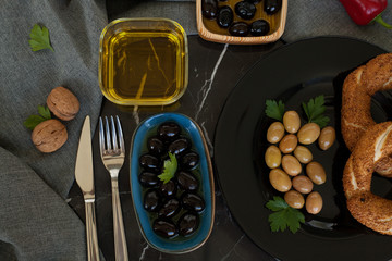 Olives and olives, olive oil on a beautiful stylish dishes, with Cutlery, on a dark background garlic, dill and fresh bread with cereals. The concept of olive products.