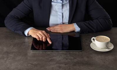 Obraz na płótnie Canvas Business woman working on tablet with dark background and copyspace