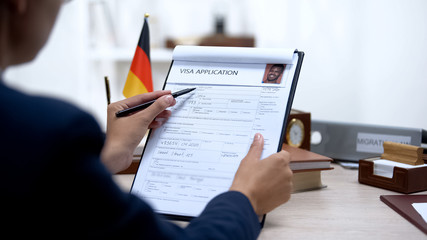 Immigration officer checking visa application office, german flag, migration