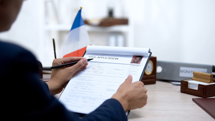 Embassy employee checking visa application office, french flag, migration
