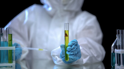 Oil lab worker examining composition of fuel marked as extremely flammable