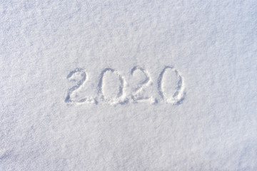 Text 2020 written on white fresh snow in sunny winter day. Merry Christmas and Happy New Year. Winter holiday concept