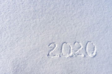 Text 2020 written on white fresh snow in sunny winter day. Merry Christmas and Happy New Year. Winter holiday concept