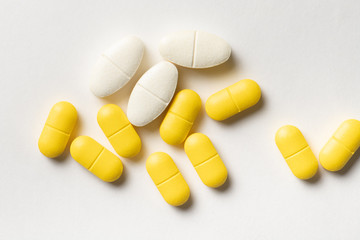 White and yellow drug pills on white background
