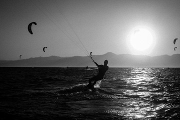 Silhouette of surfer people riding on surfboard in the sunset. Panoramic style with black and white...