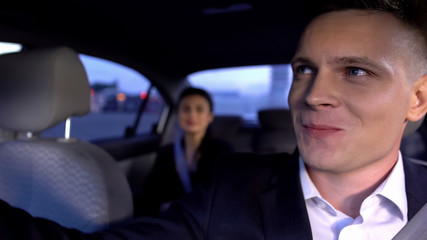 Handsome male in suit looking at female in auto and smiling, feeling affection