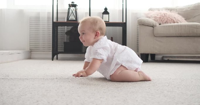 Cute baby girl crawling on carpet at apartment