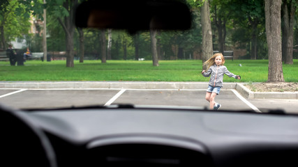 Female kid running front driving car, road traffic safety rules, accident risk
