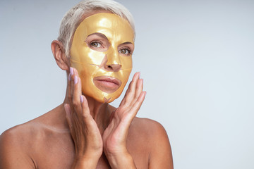 Beautiful aged woman doing face mask at home