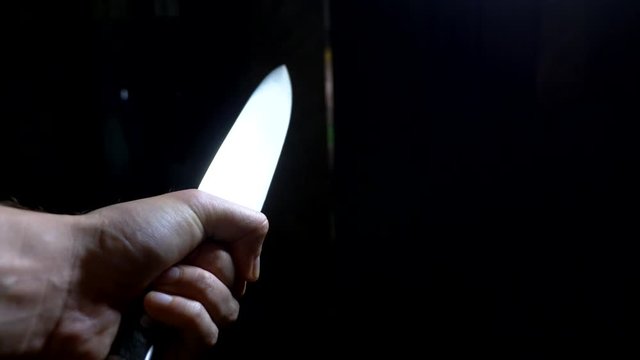 concept of halloween, violence. first-person view. male hand with a knife moves along a dark corridor