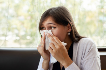 Brunette woman blowing nose into tissue